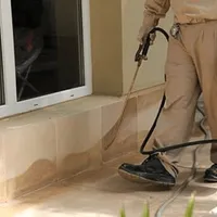 General pest control technician spraying exterior perimeter around a home in Nashua, NH